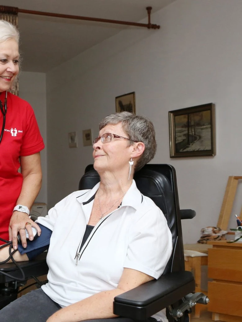 Péče o seniorku v domácnosti s měřením krevního tlaku.