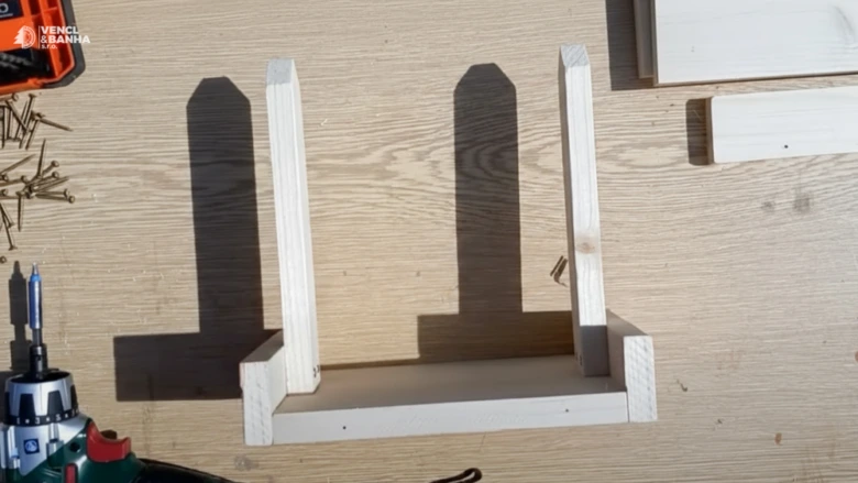 Částečně sestavené dřevěné krmítko pro ptáky na pracovní ploše.