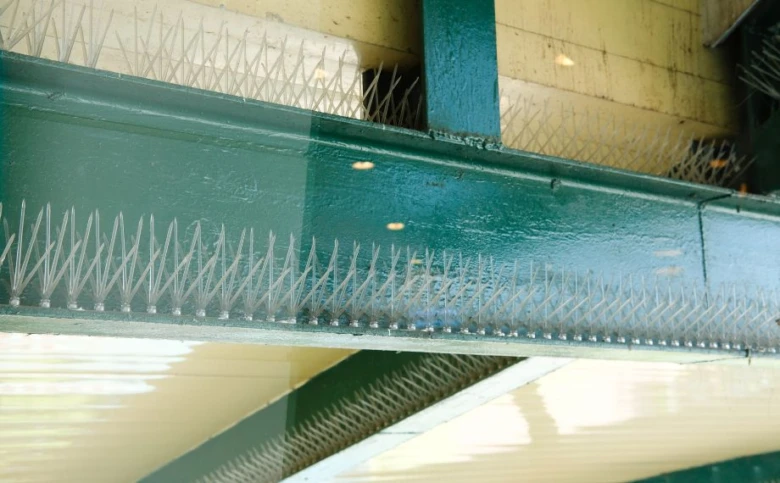Bílé antipichové špičky na zeleném balkóně pro odraz holubů.