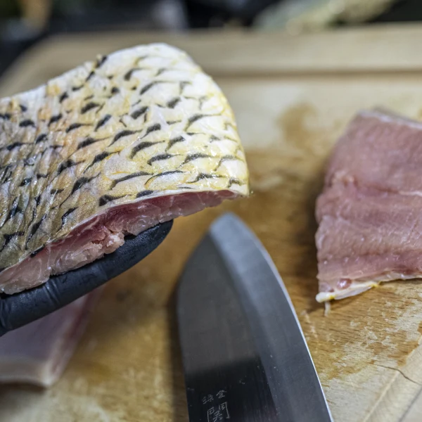 Surový filet amurského bílého ryby s kůží na dřevěném prknu.