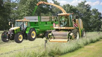 Traktor s přívěsem pro senařování na louce během sklizně.