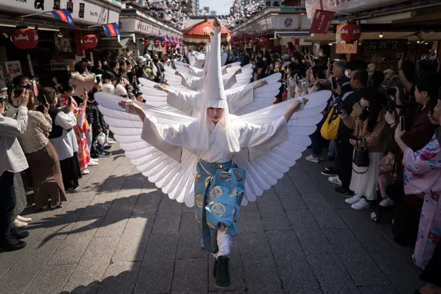 Osoba v kostýmu ptáka s křídly na japonském slavnostním průvodu.