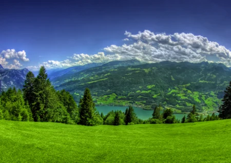 Zelená krajina s horami jezerem pod oblohou.