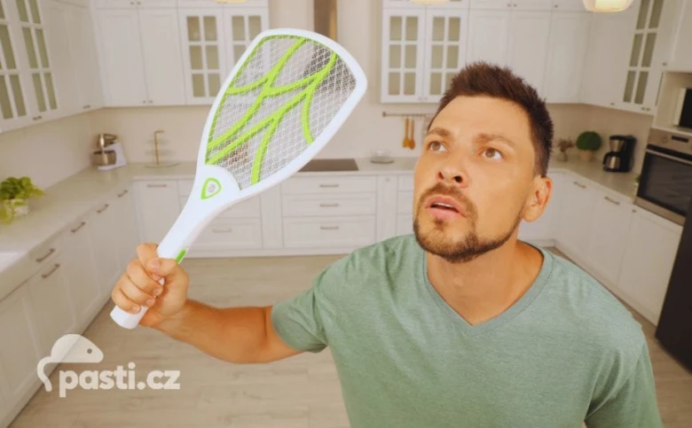 Muž drží elektrický zabíječ hmyzu v kuchyni.