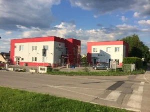 Moderní červené bytové domy na pozadí modré oblohy.